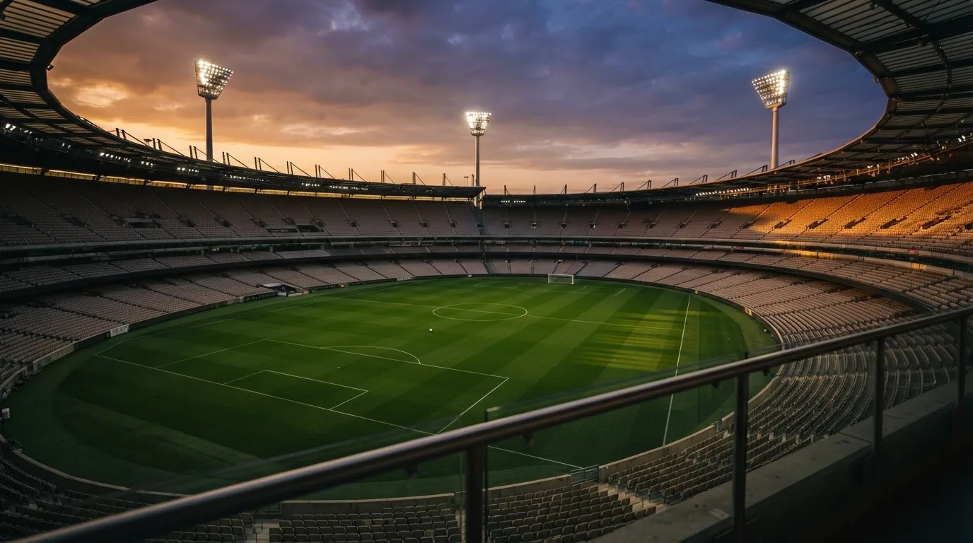 Un estadio de fútbol vacío con torres de iluminación al atardecer