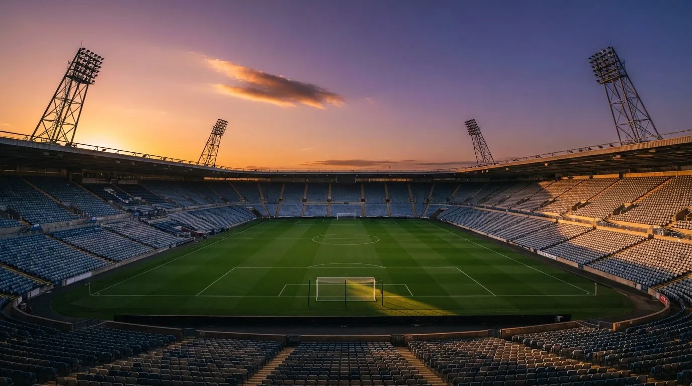 Un estadio de fútbol vacío con torres de iluminación al atardecer