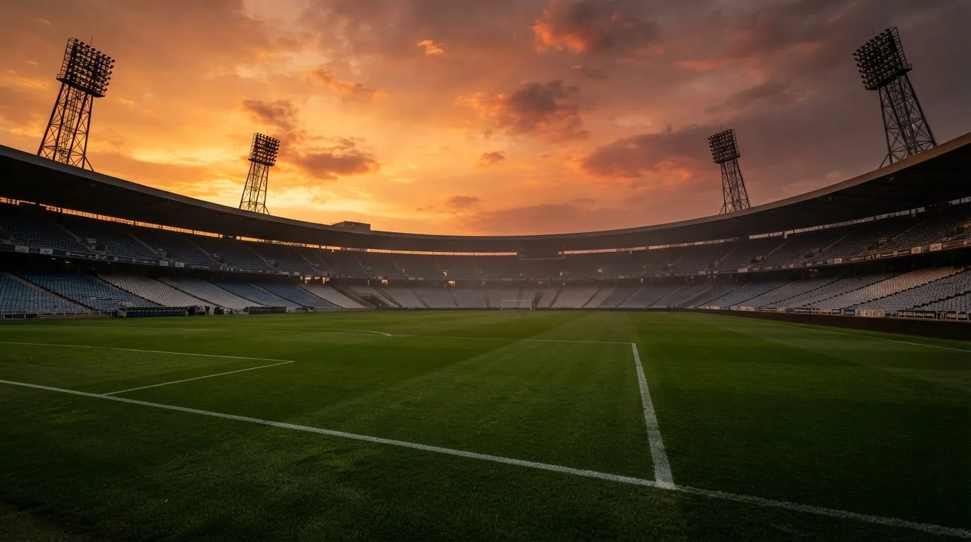 Un estadio de fútbol vacío con torres de iluminación al atardecer