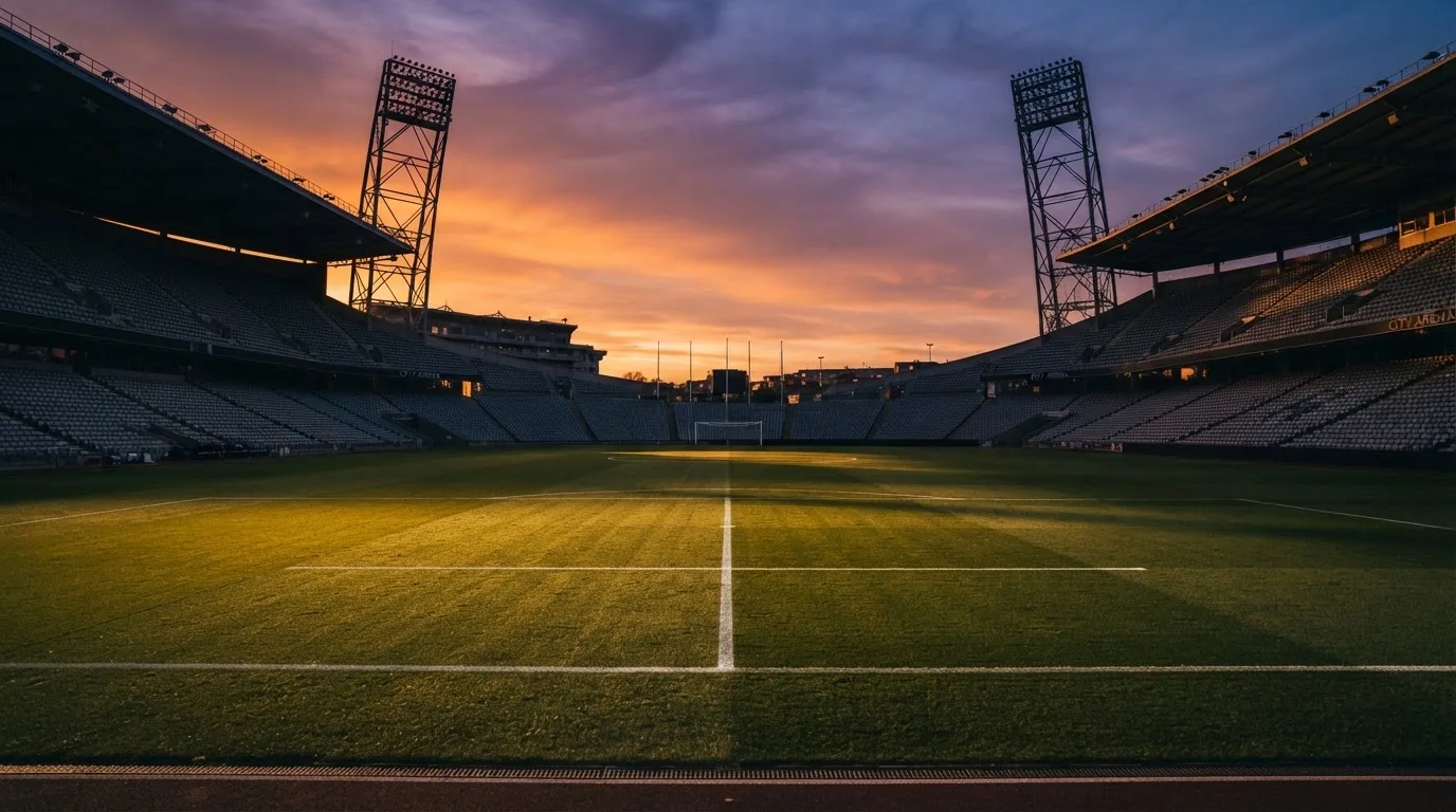 Un estadio de fútbol vacío con torres de iluminación al atardecer