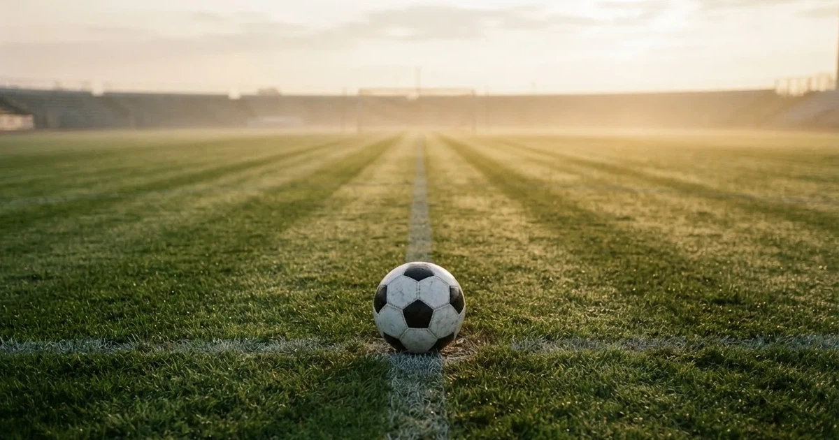 Un balón en el punto central de un campo de césped a la luz de la mañana