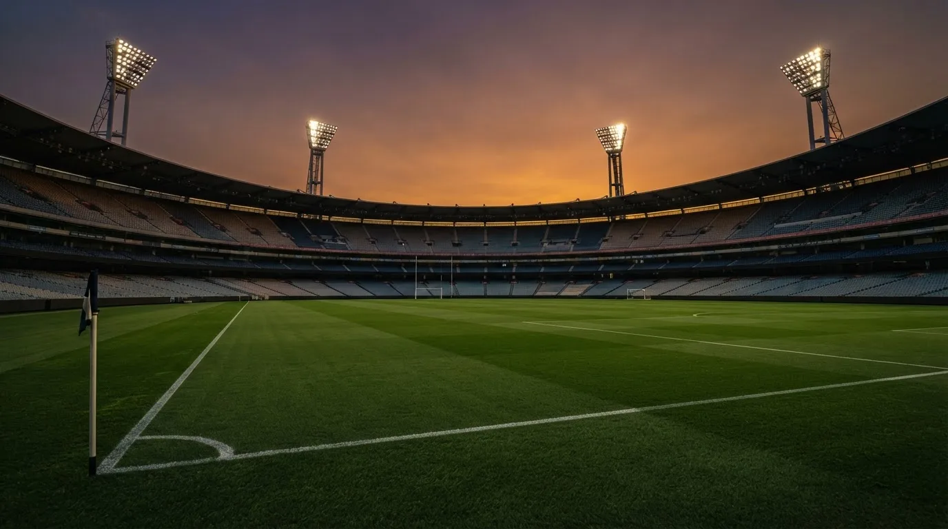 Un estadio de fútbol vacío con torres de iluminación al atardecer