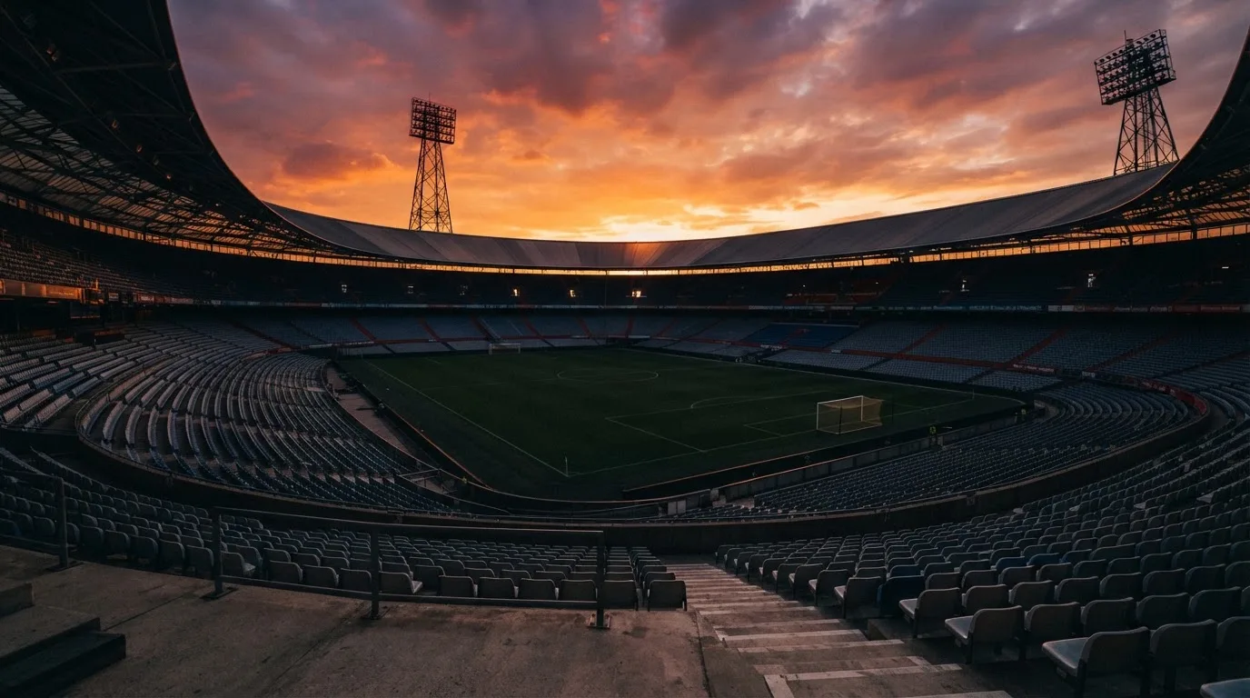 Un estadio de fútbol vacío con torres de iluminación al atardecer