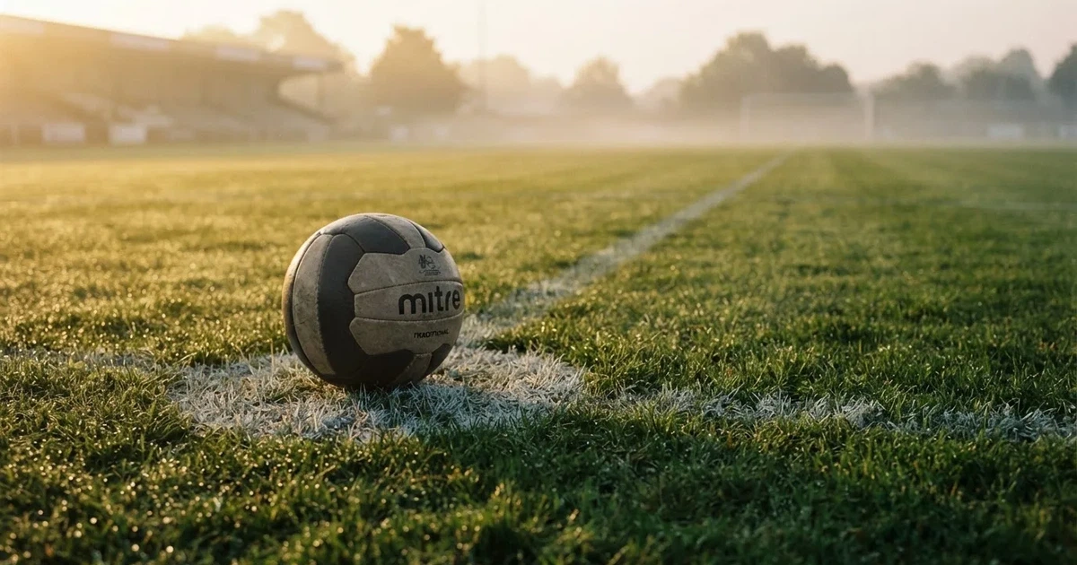 Un balón en el punto central de un campo de césped a la luz de la mañana