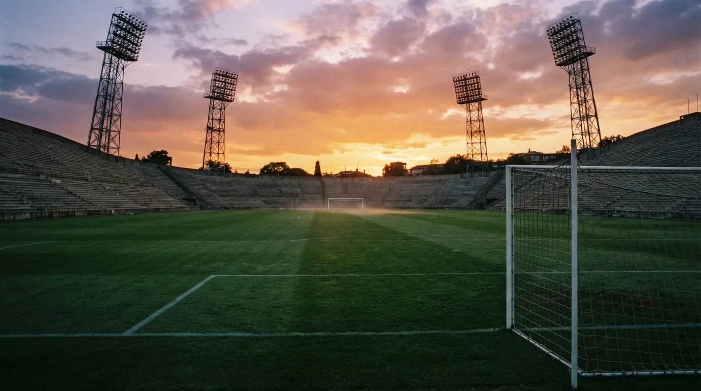 Un estadio de fútbol vacío con torres de iluminación al atardecer