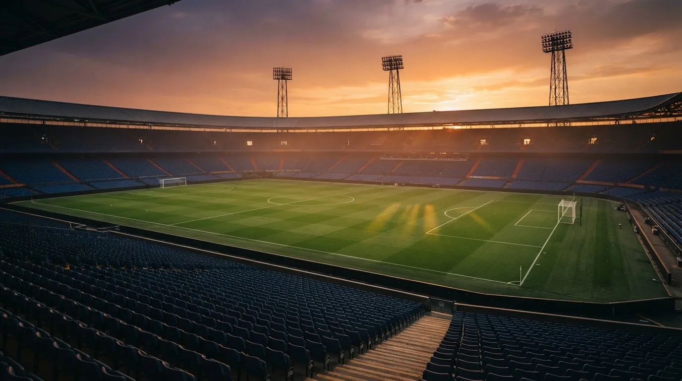Un estadio de fútbol vacío con torres de iluminación al atardecer