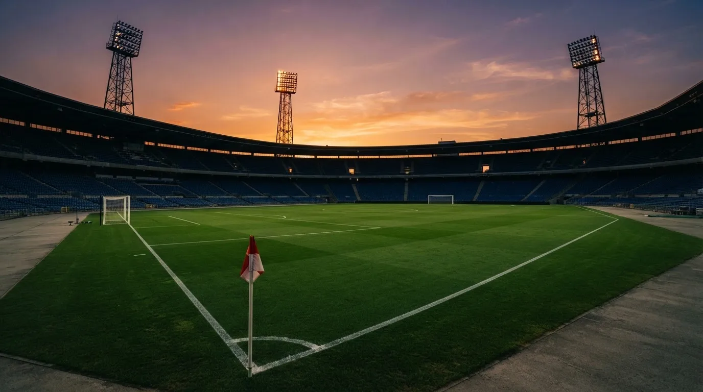 Un estadio de fútbol vacío con torres de iluminación al atardecer
