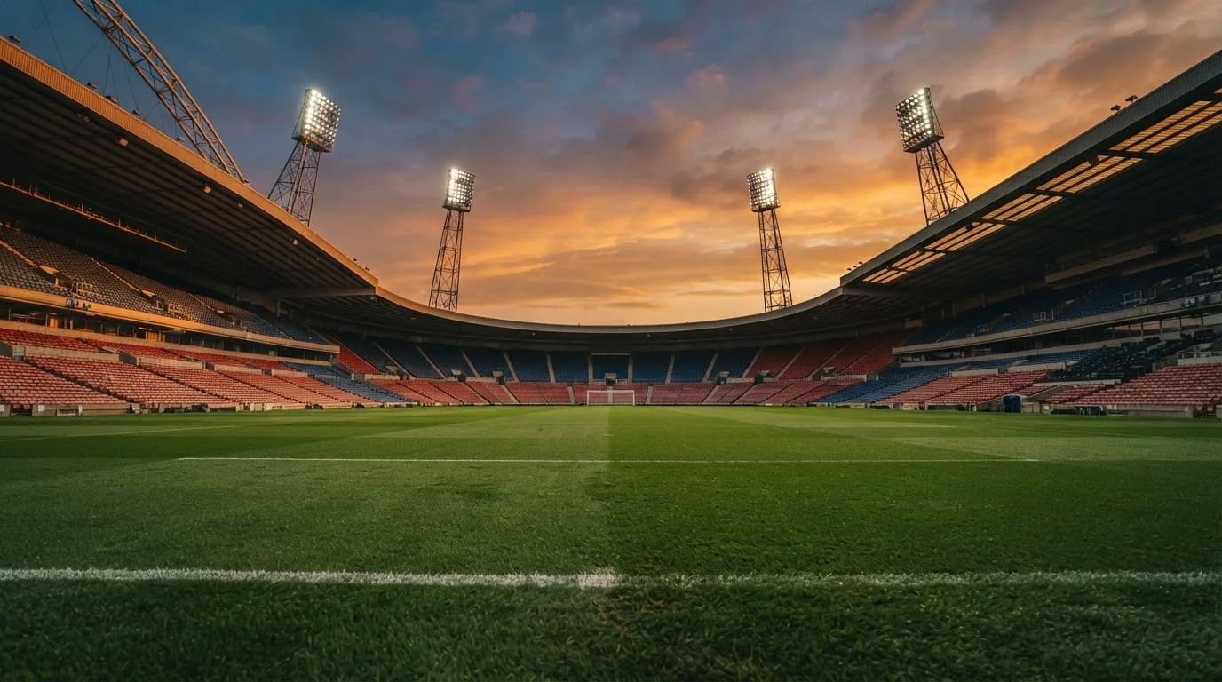 Un estadio de fútbol vacío con torres de iluminación al atardecer