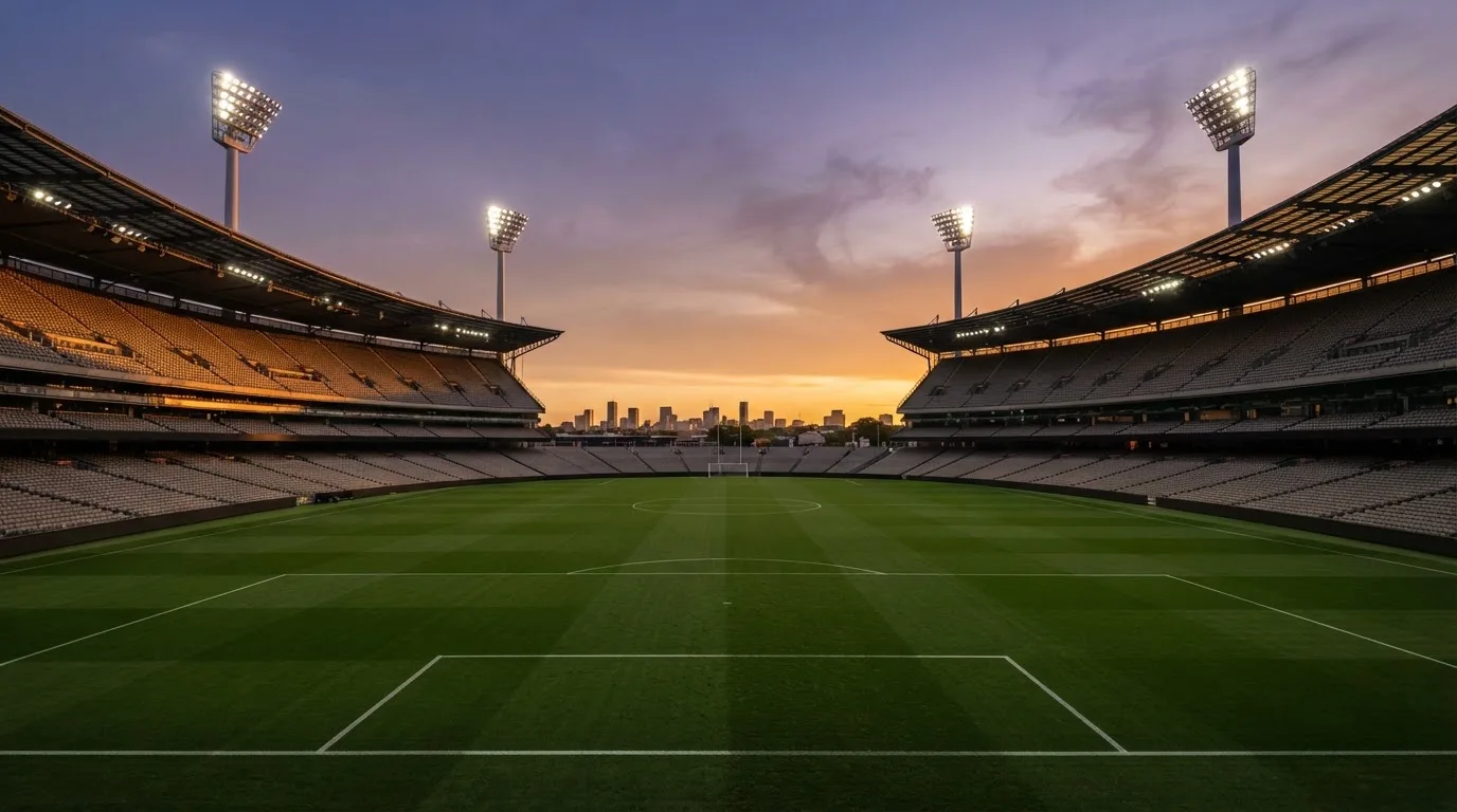 Un estadio de fútbol vacío con torres de iluminación al atardecer