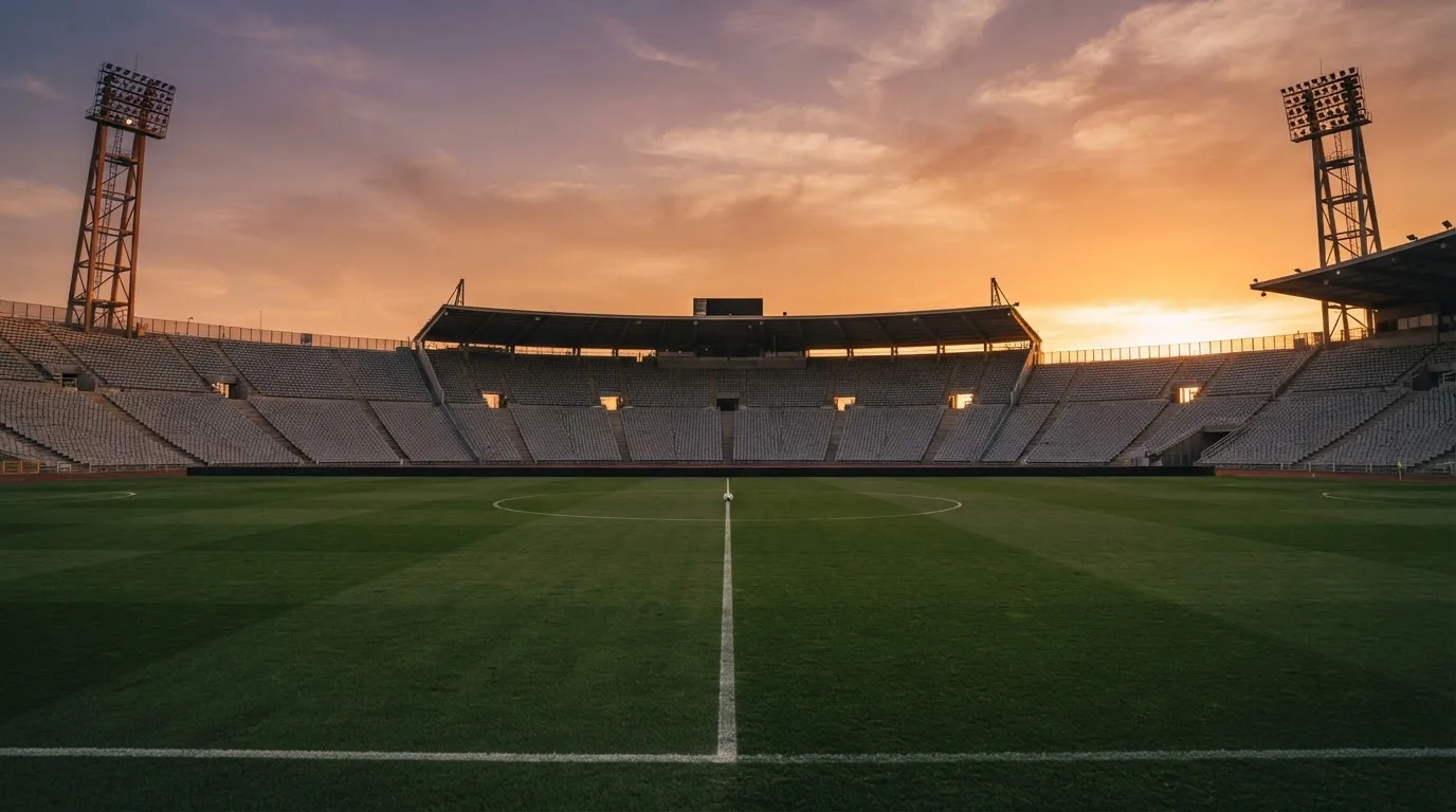 Un estadio de fútbol vacío con torres de iluminación al atardecer