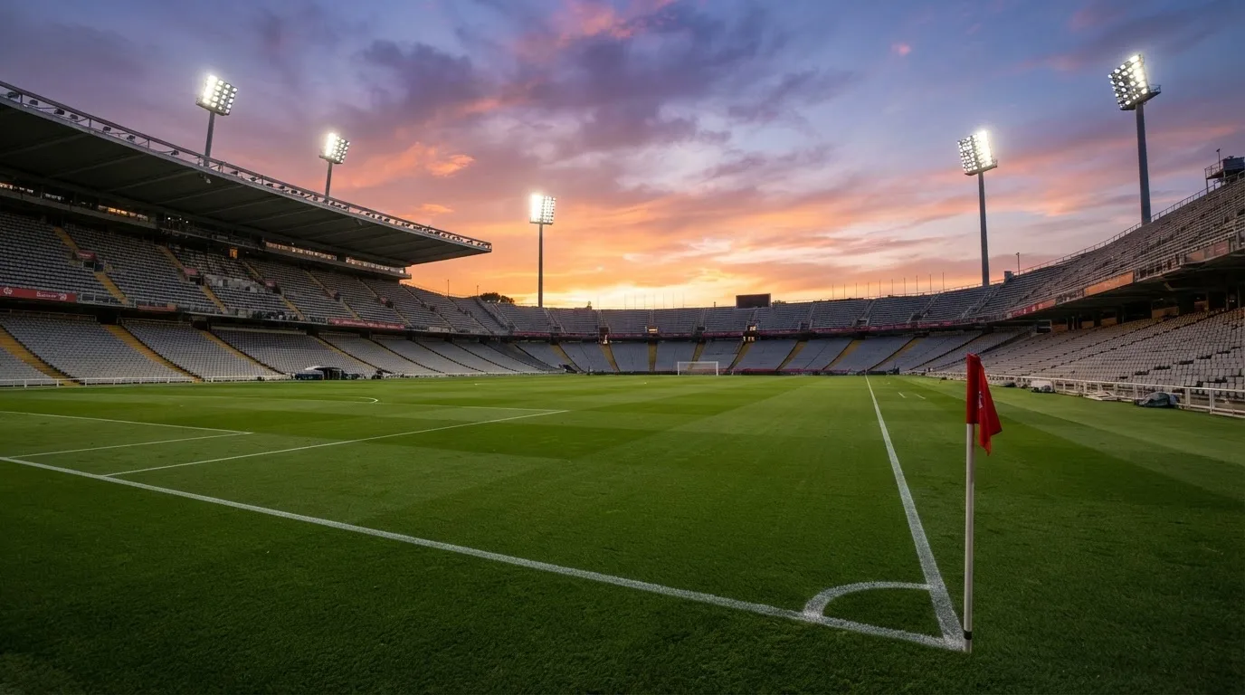 Un estadio de fútbol vacío con torres de iluminación al atardecer