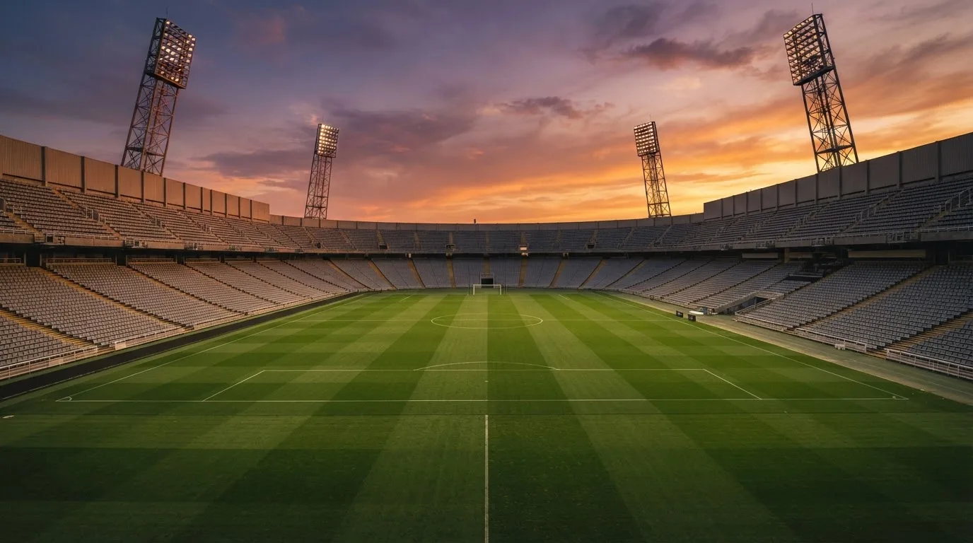 Un estadio de fútbol vacío con torres de iluminación al atardecer