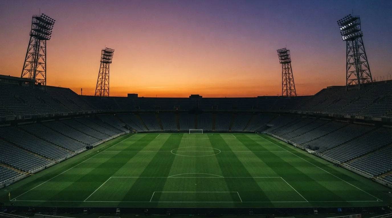 Un estadio de fútbol vacío con torres de iluminación al atardecer