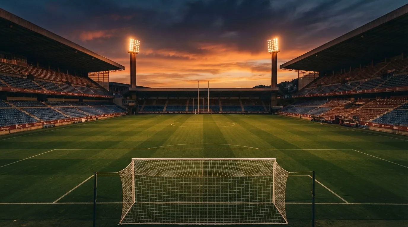 Un estadio de fútbol vacío con torres de iluminación al atardecer
