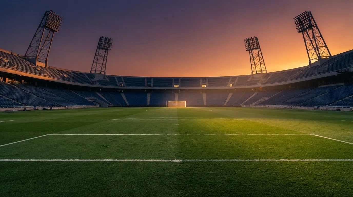 Un estadio de fútbol vacío con torres de iluminación al atardecer