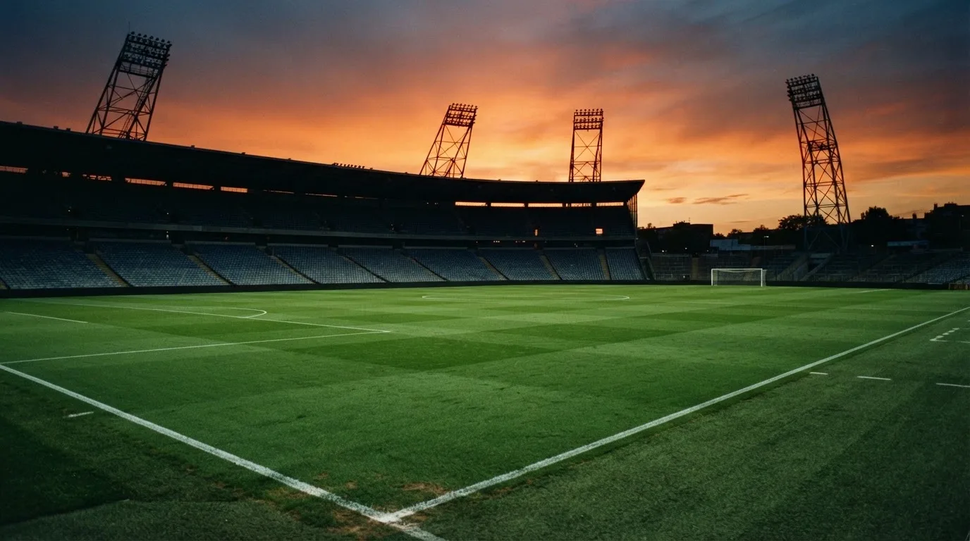 Un estadio de fútbol vacío con torres de iluminación al atardecer