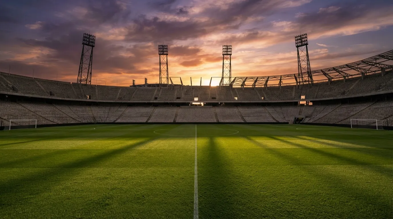 Un estadio de fútbol vacío con torres de iluminación al atardecer