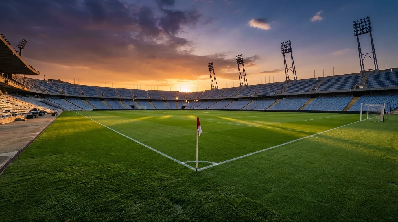 Un estadio de fútbol vacío con torres de iluminación al atardecer