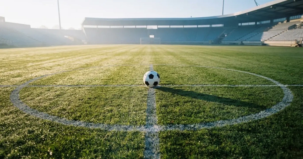 Un balón en el punto central de un campo de césped a la luz de la mañana