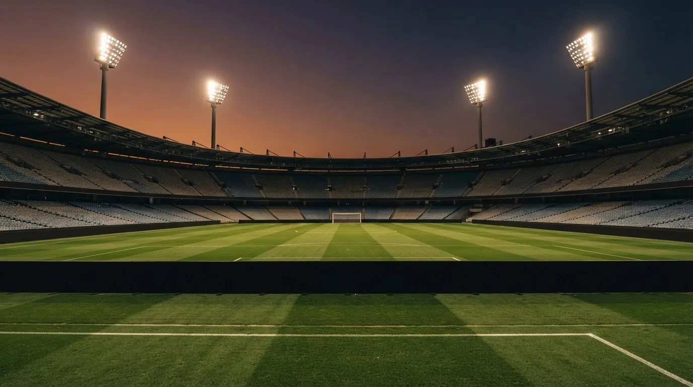 Un estadio de fútbol vacío con torres de iluminación al atardecer