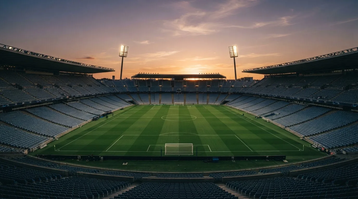 Un estadio de fútbol vacío con torres de iluminación al atardecer