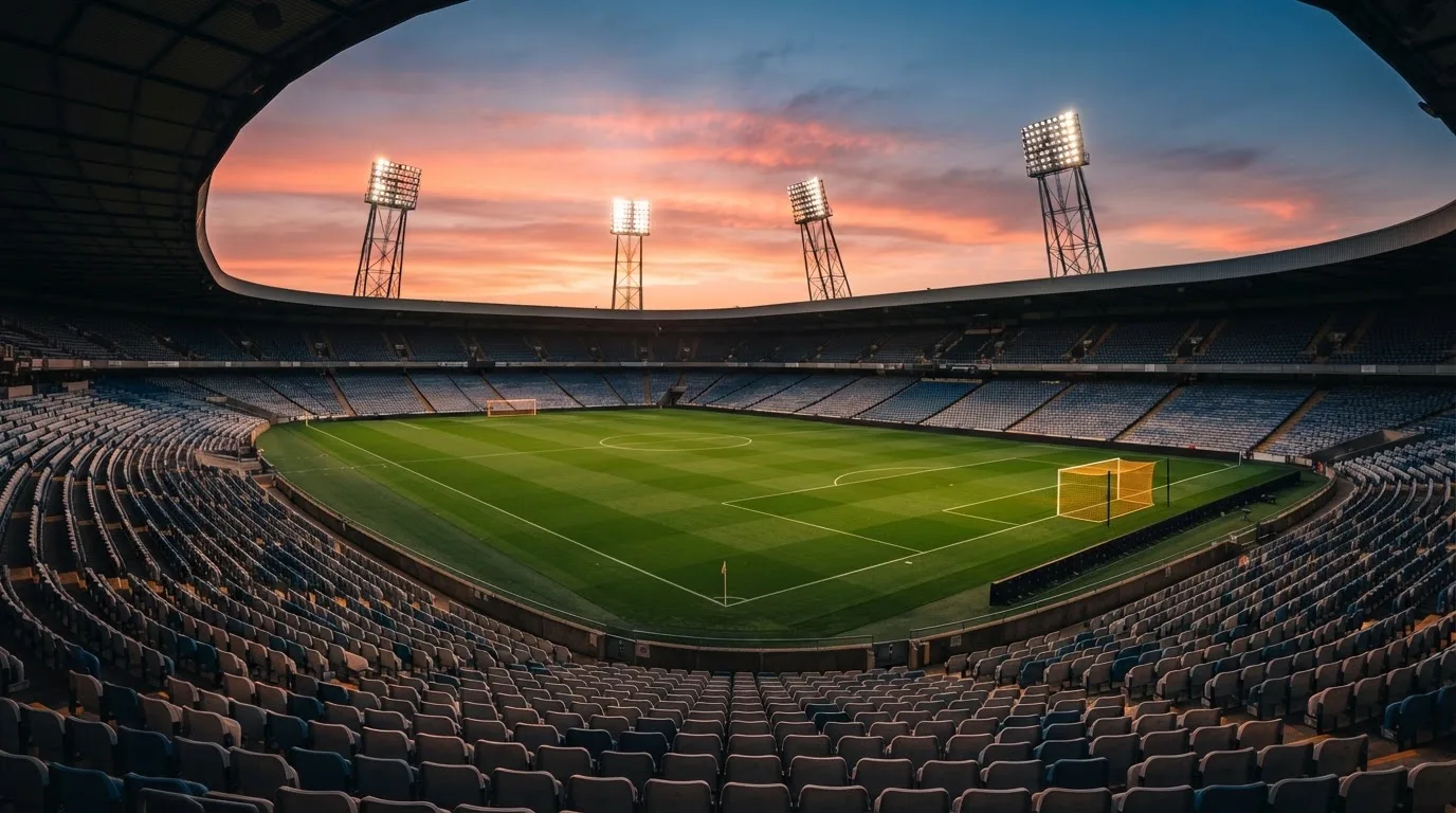 Un estadio de fútbol vacío con torres de iluminación al atardecer