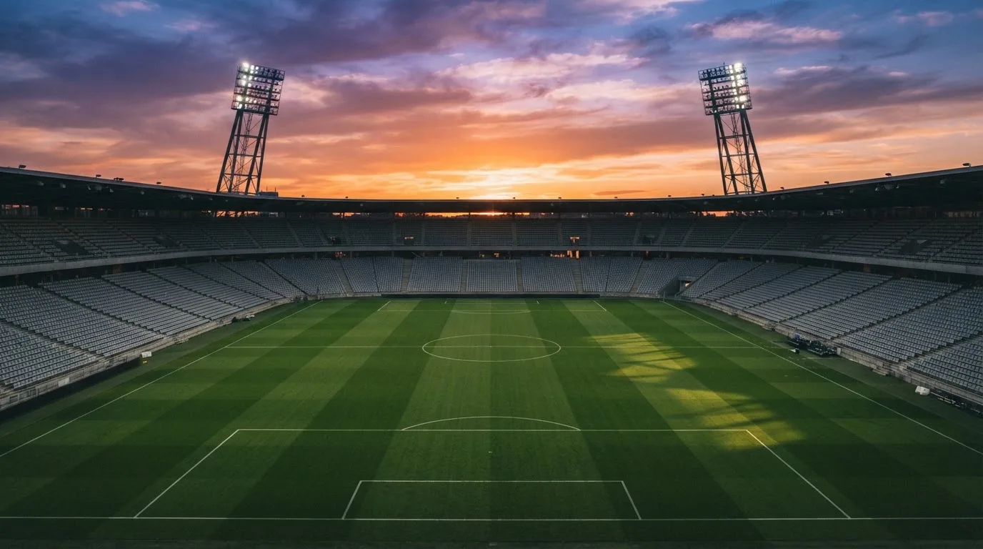 Un estadio de fútbol vacío con torres de iluminación al atardecer