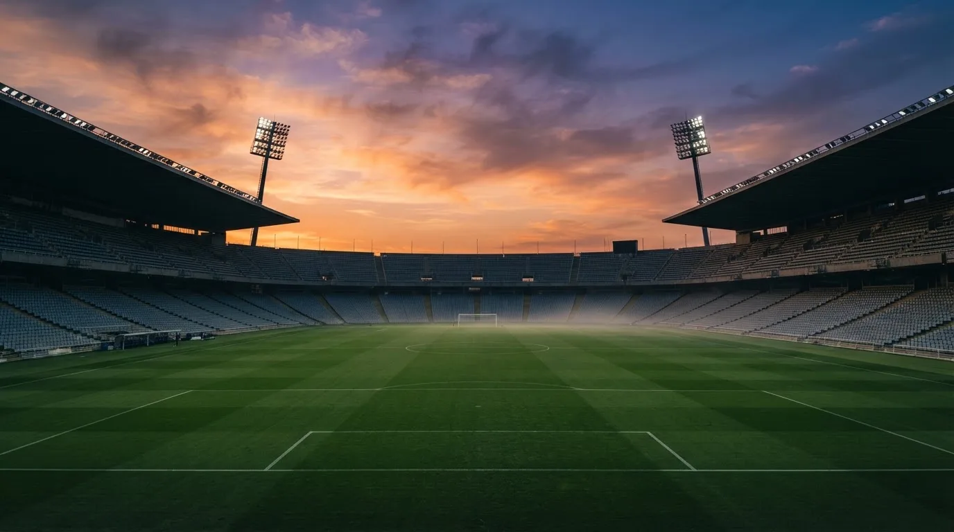Un estadio de fútbol vacío con torres de iluminación al atardecer