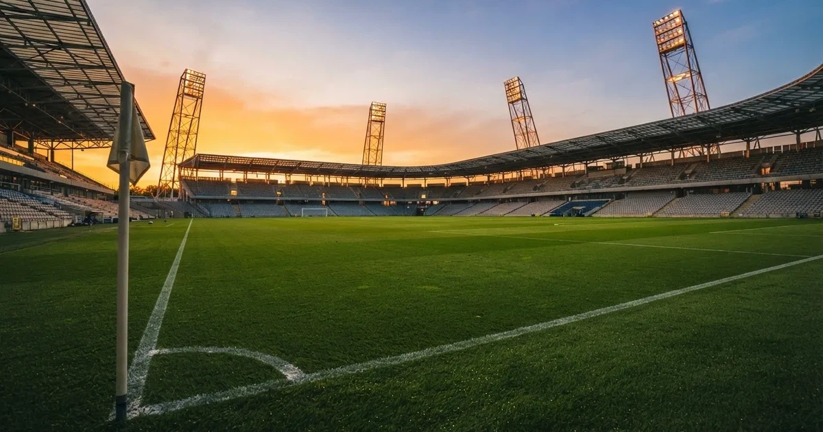 Un estadio de fútbol vacío con torres de iluminación al atardecer